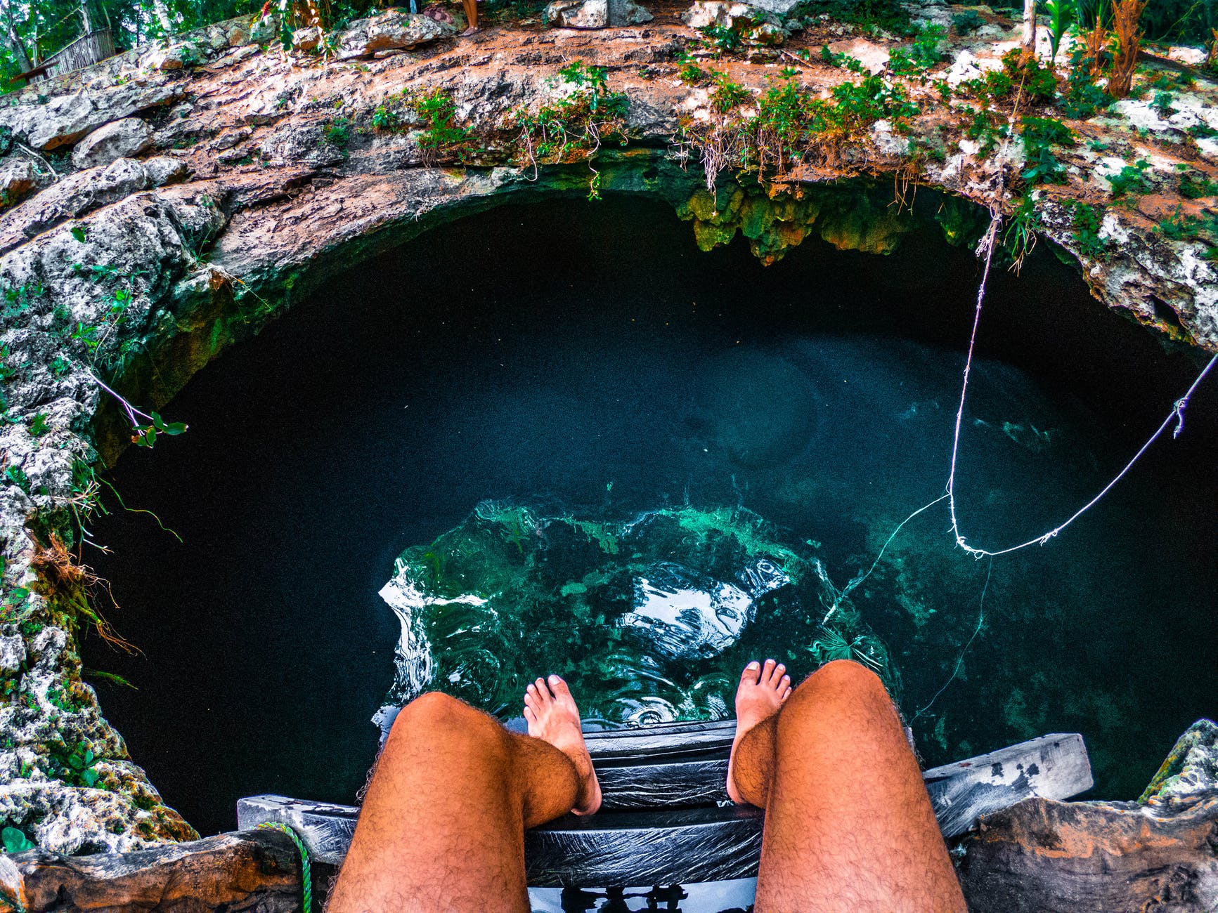 person sitting on a ladder with view of underground water