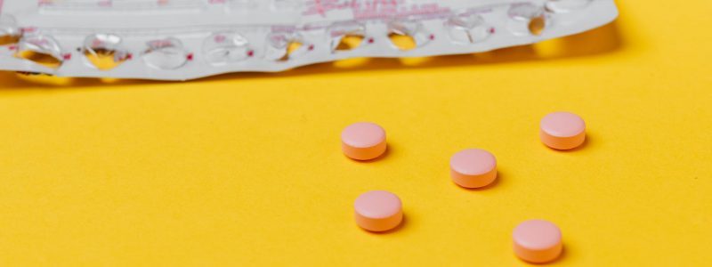 pink pills on yellow surface