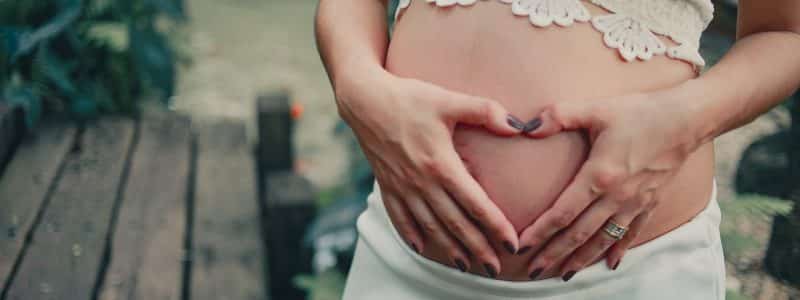 pregnant woman wearing white skirt holding her tummy