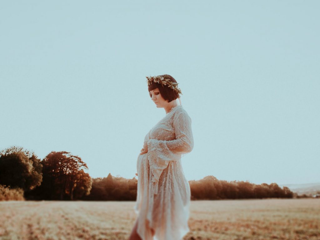 young pregnant woman in grassy field