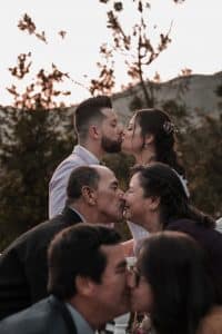 elegant ethnic newlyweds and parents kissing on wedding day outdoors