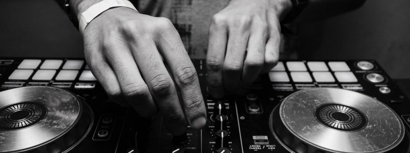grayscale photography of person using dj controller