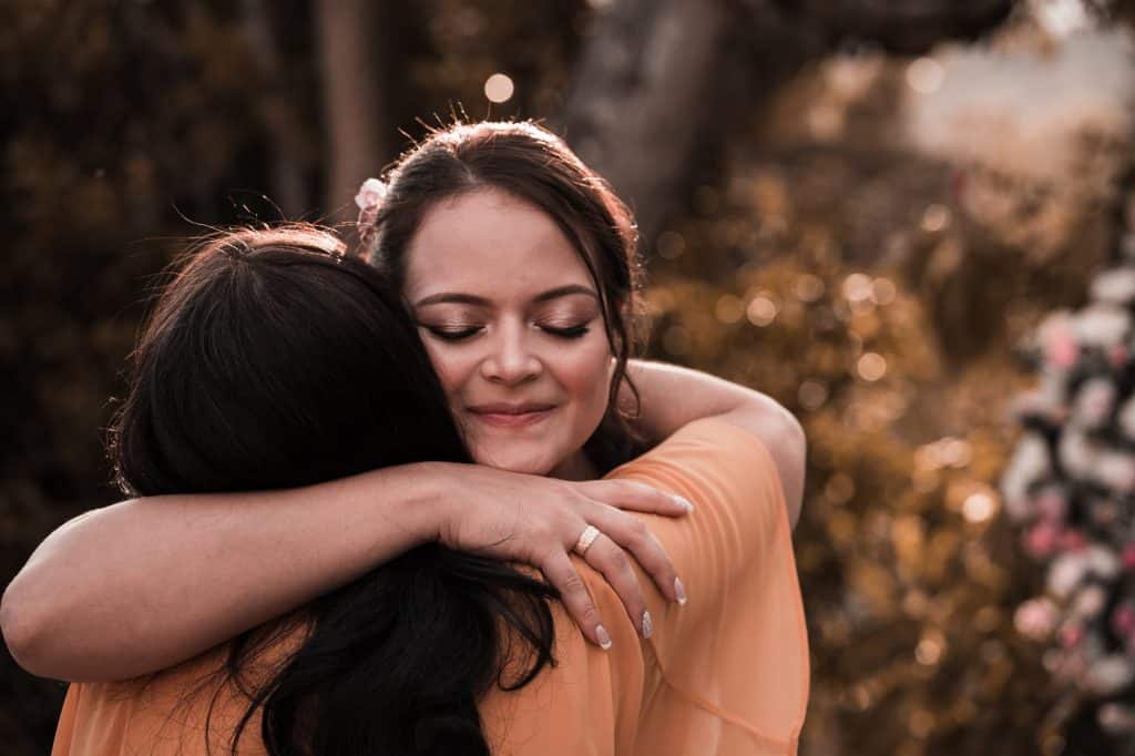 content ethnic woman embracing unrecognizable girlfriend in daylight