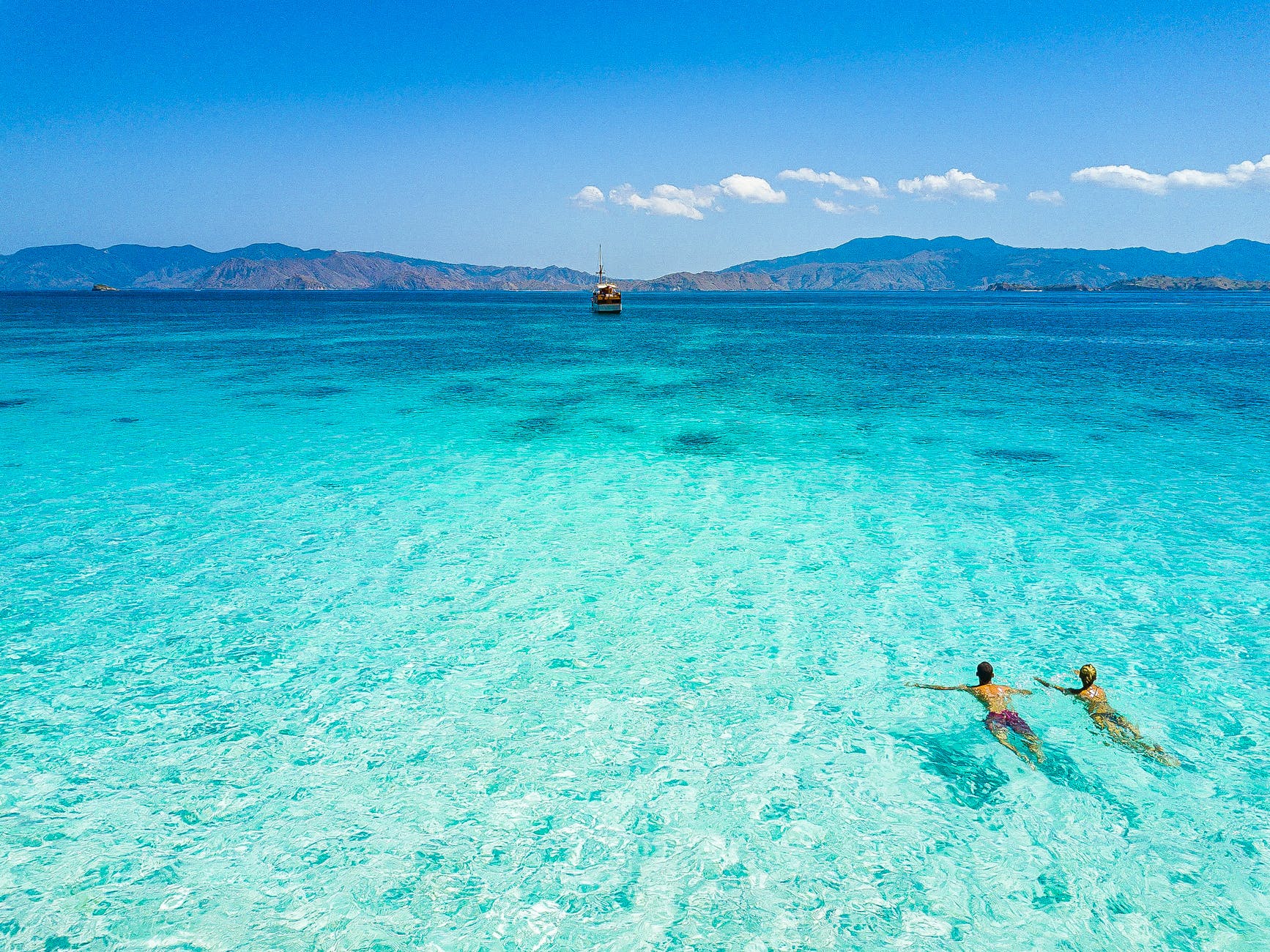 couple swimming in blue sea under blue sky