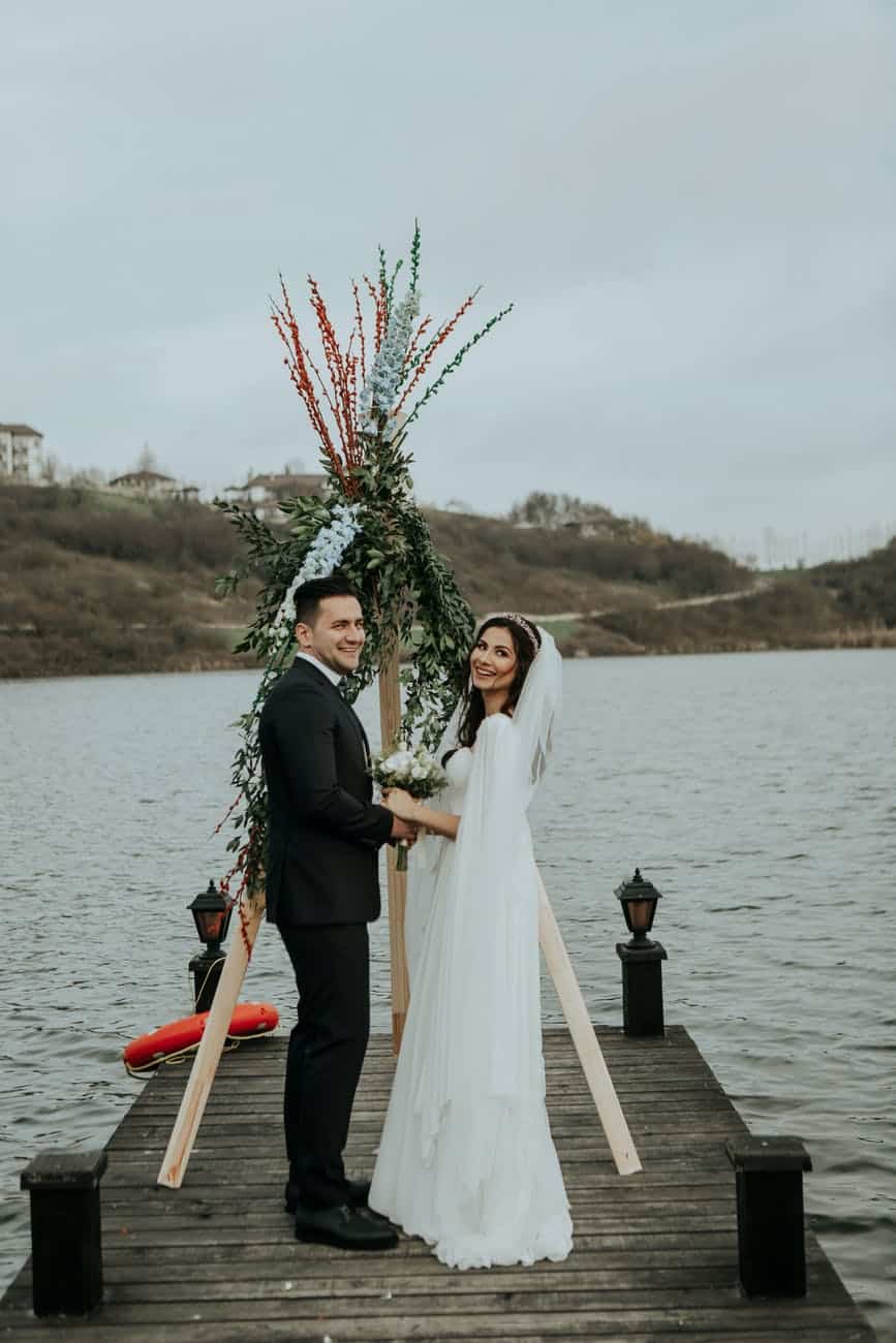happy bride and groom standing on pier
