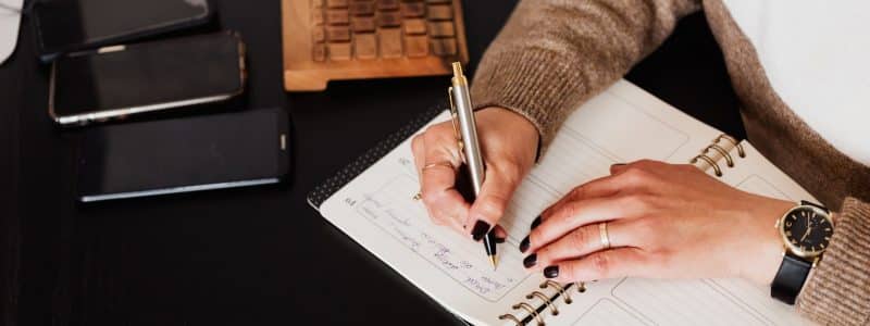 crop stylish woman writing in notebook