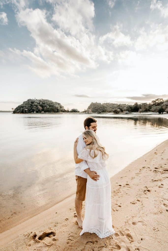 happy couple embracing on sandy sea shore during honeymoon