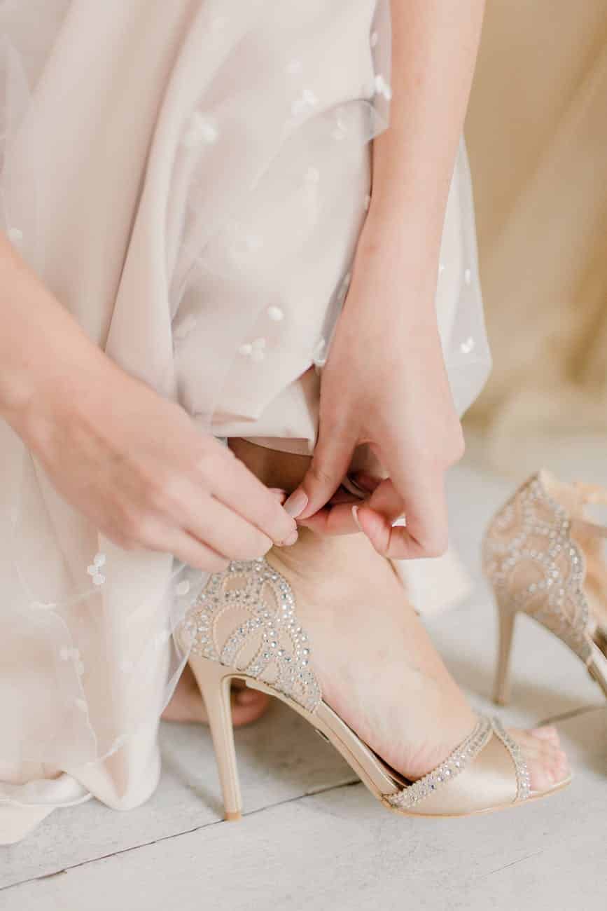 bride in wedding dress putting shoes on