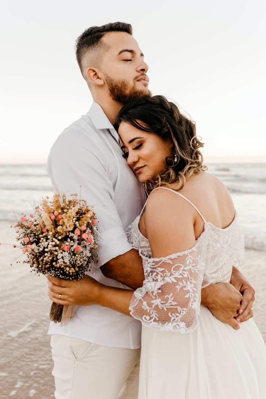 newlywed couple embracing on beach