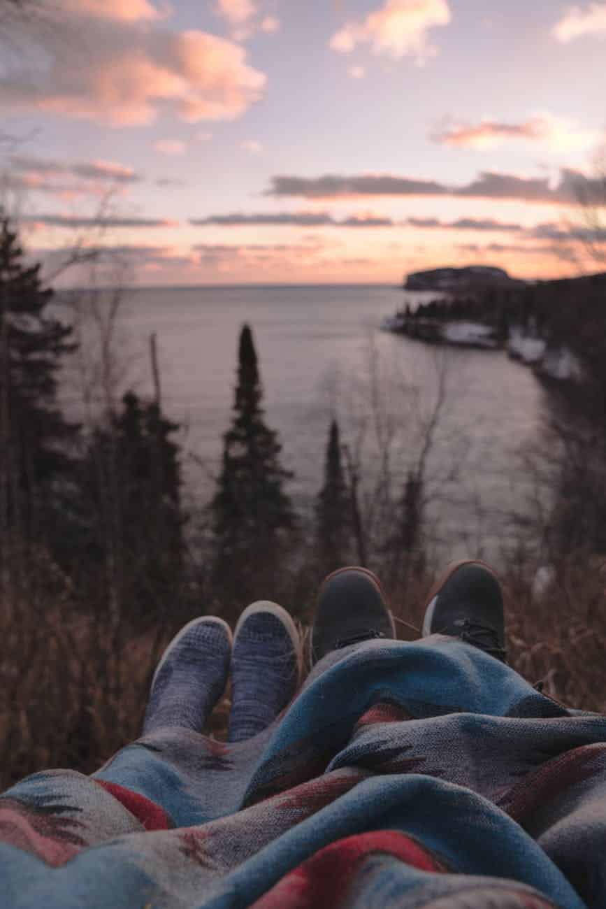 anonymous couple lying on hill at seaside and enjoying sunset time
