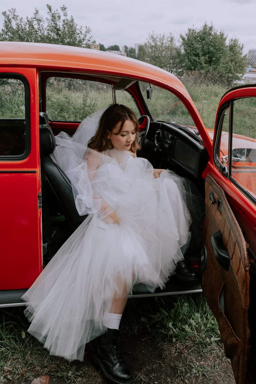 woman in white dress sitting on red car