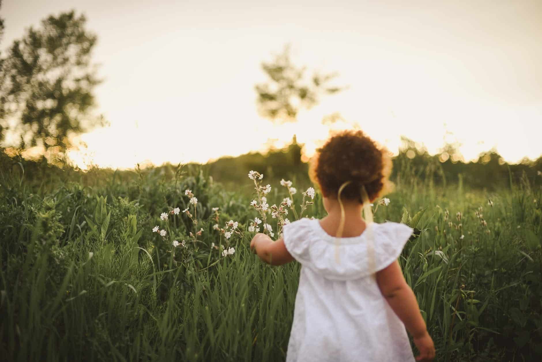 girl standing beside white flower field