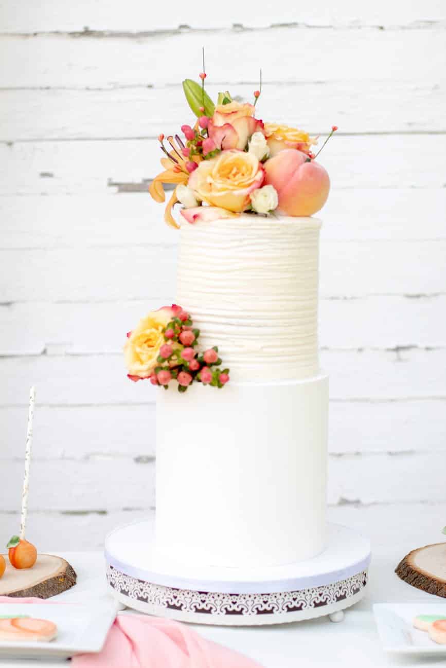 shallow focus photo of yellow and pink flowers on two tier cake