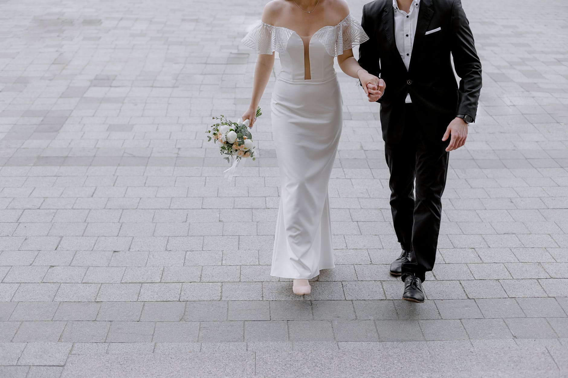 man in black suit holding hand of woman in white wedding dress