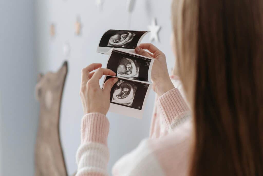 femme qui pensait être heureuse pendant ma grossesse et qui regarde avec émotion les échographies de son bébé 