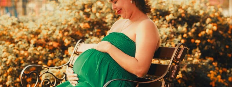 femme enceinte assise sur un banc qui touche son ventre