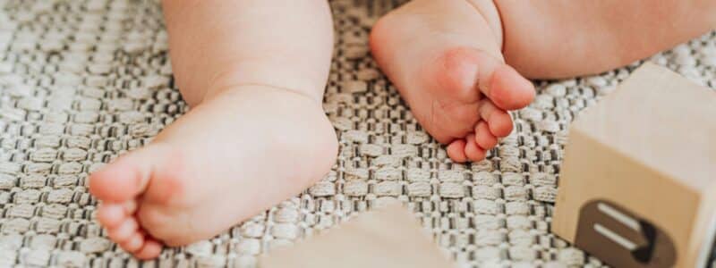 un bébé qui joue avec des cubes à qui il faudrait mettre à disposition des jouets d'éveil noir et blanc