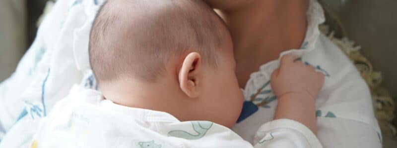 bébé dans les bras de sa maman pendant que ses parents vivent un baby clash