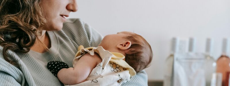 Maman avec un bébé dans les bras qui peut profiter et se sentir bien grâce à tous les indispensables en post-partum auxquels elle a pensé en amont