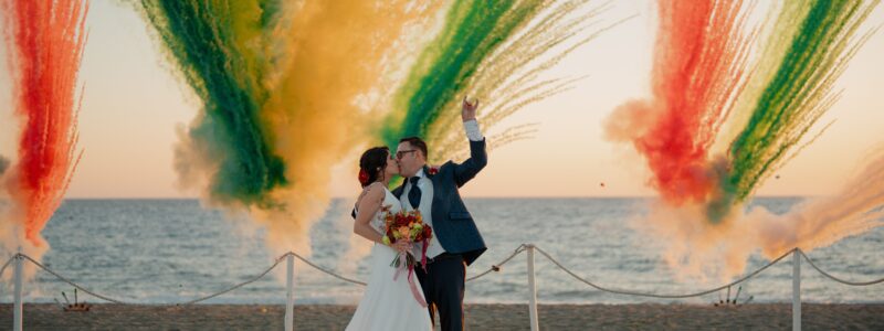 photo de mariés qui s'embrassent avec en fond un feu de jour coloré qui est une tendance actuelle dans les mariages