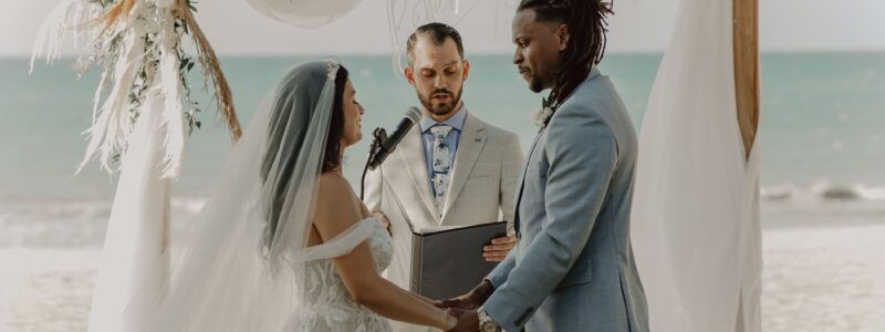 mariés sur la plage lors de leur cérémonie laïque en train d'échanger leurs voeux de mariage