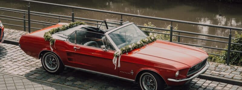 location de voiture de mariage avec une cabriolet rouge décorée avec une guirlande de fleurs et de feuillage