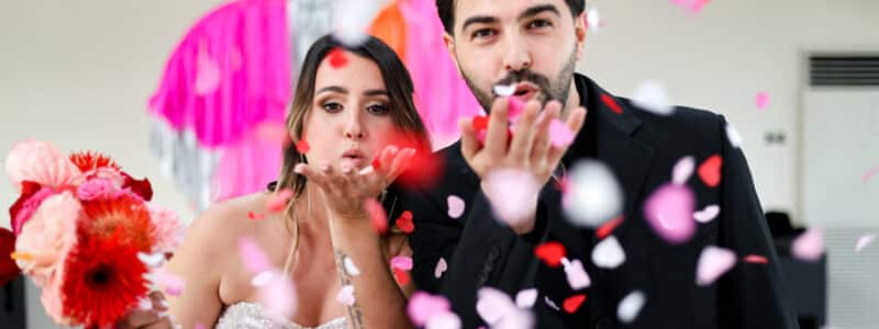 couple de mariés très rock'n'roll qui soufflent sur des confettis colorés