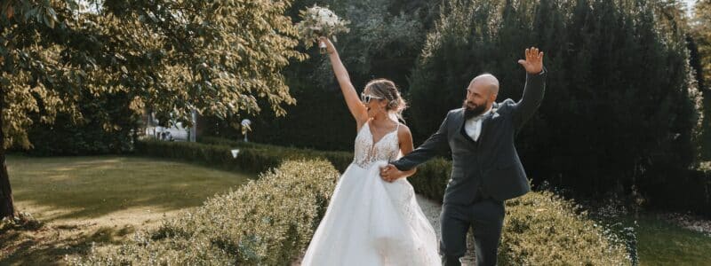 photo de mariés heureux qui partent faire leur photo de couple le jour de leur mariage